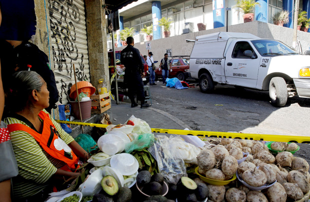 ATTENTION EDITORS - VISUAL COVERAGE OF SCENES OF INJURY OR DEATH A police officer and forensic technicians stand at a crime scene where a man lies dead after being killed by unknown assailants outside a building in Chilpancingo, Guerrero state, Mexico November 15, 2017. REUTERS/Henry Romero ORG XMIT: GGGHNR01