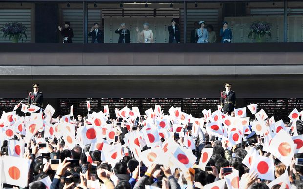 People wave national flags to celebrate the 84th birthday of Japan's Emperor Akihito (top-3rd L) at the Imperial Palace in Tokyo on December 23, 2017, as other members of Japan's royal family wave to the crowd. Japan's Emperor Akihito, who plans to abdicate in 2019, made an appearance to mark his 84th birthday, celebrated as a holiday across the country. / AFP PHOTO / Toru YAMANAKA