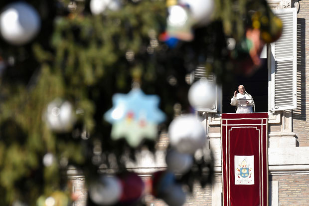 Pope Francis speaks from the window of the apostolic palace overlooking St Peter's square during the Sunday Angelus prayer, on December 24, 2017, in the Vatican. / AFP PHOTO / ANDREAS SOLARO