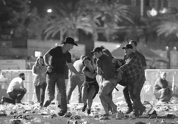 TOPSHOT - LAS VEGAS, NV - OCTOBER 01: (EDITORS NOTE: Image contains graphic content.) People carry a peson at the Route 91 Harvest country music festival after apparent gun fire was heard on October 1, 2017 in Las Vegas, Nevada. There are reports of an active shooter around the Mandalay Bay Resort and Casino. David Becker/Getty Images/AFP / AFP PHOTO / GETTY IMAGES NORTH AMERICA / David Becker