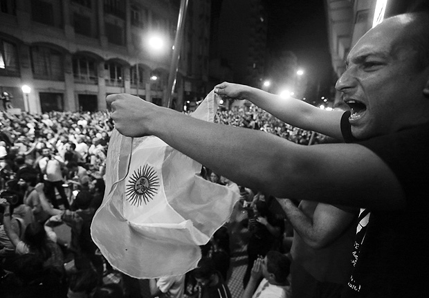 A demonstrator waves an Argentine flag as a crowd marches to the Congress to protest against a pension reform in Buenos Aires, Argentina, Tuesday, Dec. 19, 2017. Demonstrators in several neighborhoods of Buenos Aires banged on pots Monday night to protest the measure and marched to Congress. The protests hold deep symbolism for Argentines, who recall Argentina's worst economic crisis in 2001-2002, when pot-banging marches forced presidents from office. (AP Photo/Victor R. Caivano) ORG XMIT: VC105