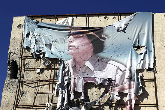 Imagem de Gaddafi em banner semidestrudo em Sirte, cidade natal do ditador lbio e onde ele foi morto 