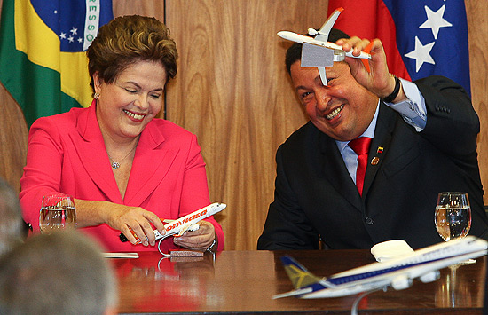 O presidente da Venezuela, Hugo Chaves, durante encontro com a presidente Dilma Rousseff, segurando um aviao da Embraer