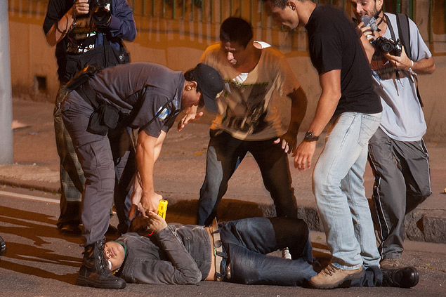 Policial usa arma de choque em manifestante cado no cho prximo  sede do governo fluminense