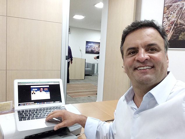 O candidato tucano Acio Neves tira selfie com sua pgina do Twitter ao fundo
