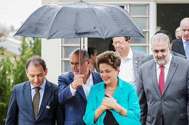 Geraldo Alckmin segura guarda-chuva para Dilma Roussef durante entrega de casas em Catanduva (SP)