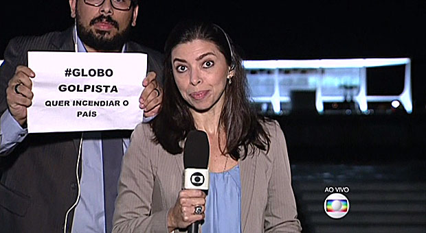 Manifestante entra ao vivo no "Jornal da Globo" com cartaz de protesto contra a emissora.