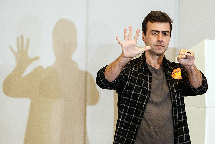 Rio de Janeiro's mayoral candidate, Marcelo Freixo, of the Socialism and Freedom Party (PSOL), gestures after casting his vote during the municipal elections' first round in Rio de Janeiro, Brazil, on October 2, 2016. Brazilians furious at recession and corruption voted Sunday in municipal elections amid heightened security after a series of murders of candidates. Among the first to cast his ballot in the financial capital Sao Paulo was Brazilian President Michel Temer from the center-left PMDB party, who took over the presidency in August after turning on his former leftist ally Dilma Rousseff and helping to force her from the top job in an impeachment vote. / AFP PHOTO / Yasuyoshi CHIBA
