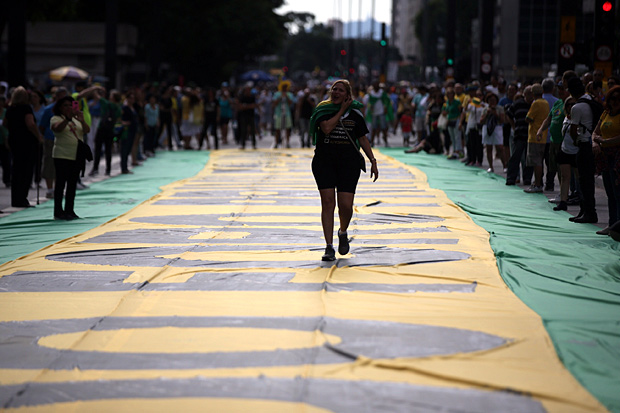 Manifestante caminha sobre faixa levada a protesto neste domingo (26) na avenida Paulista