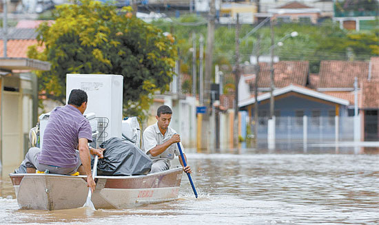 Moradores transportam objetos salvos de enchente com ajuda de barco na cidade de Atibaia, no interior de SP