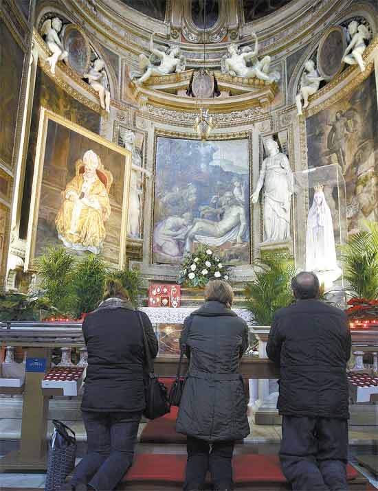 Fiis rezam diante de imagem de Joo Paulo 2, que ser beatificado em maio, em Roma
