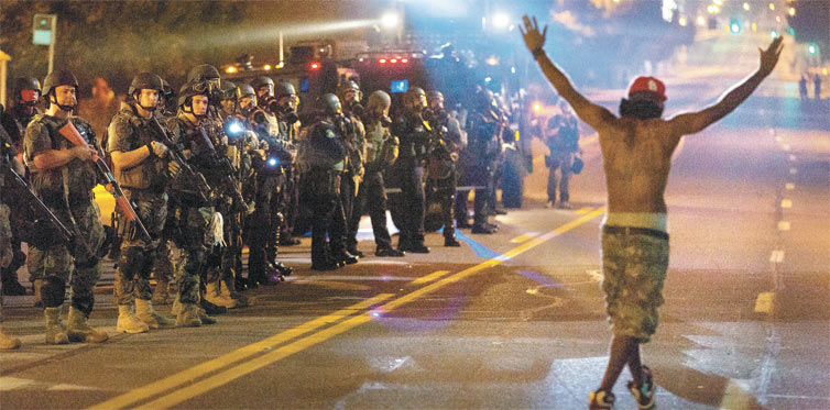 Manifestante  observado por policiais em Ferguson