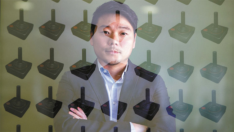 Sunami Chun, diretor-executivo da Aennova, que produz jogos, atrs de vidro ilustrado com controles do videogame Atari