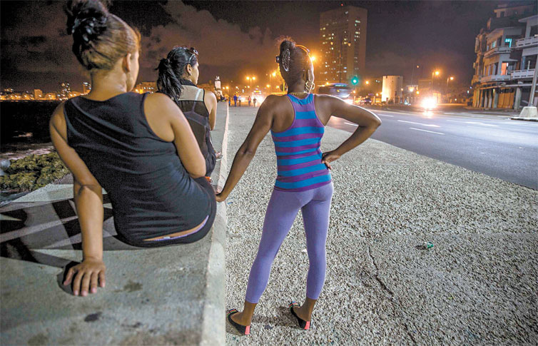 Jovens que se prostituem aguardam por clientesno Malec�n, cal�ad�o � beira-mar em Havana