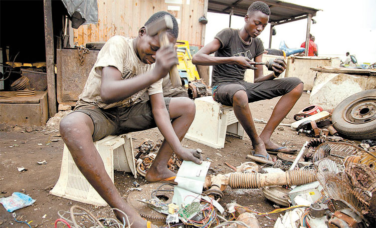 Jovens ganenses usam martelo para separar componentes eletrnicos em lixo na periferia da capital do pas, Acra