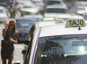 Até 15 km por dia, usar táxi é mais barato do que carro; foto mostra paulistana tentando pegar táxi em São Paulo