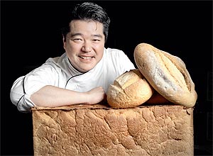 Rogério Shimura debruçado sobre pão de miga; o padeiro abre a Em Nome do Pão com Alex Atala neste semestre