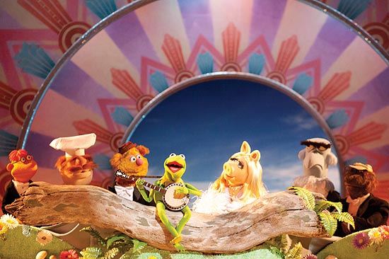 A trupe dos Muppets se reúne na roda de banjo de Caco; personagem foi rebatizado de Kermit pela Disney