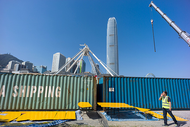 A labourer stands in front of shipping cargo containers as he shouts over to his colleagues in Hong Kong on December 12, 2016. / AFP PHOTO / Anthony WALLACE