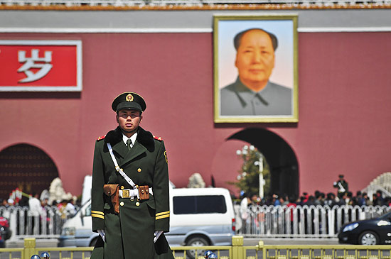 Guarda chinês diante de imagem de Mao Tsé-tung no Portão da praça da Paz Celestial; leve em conta os preços salgados dos ingressos para as principais atrações 