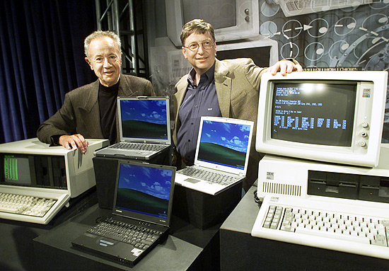 Ao lado de Andy Grove, co-fundador da Intel, o dono da Microsoft Bill Gates apoia a mão em um IBM 5150 PC