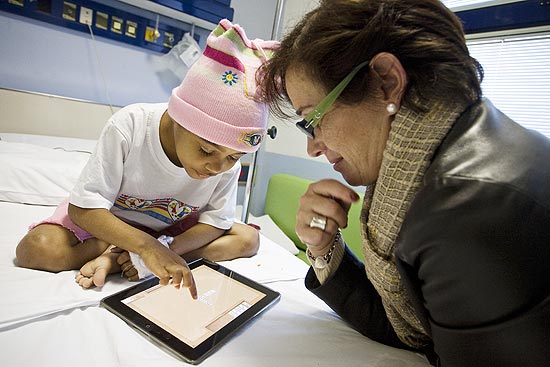 Wyslla Ferreira, 6 anos, usa iPad com a ajuda de Patrcia Pecoraro, coordenadora da brinquedoteca do Graac
