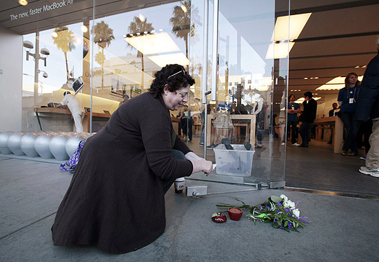 Janine Young, 53, acende uma vela em forma de ma em homenagem a Steve Jobs em frente a loja da Apple