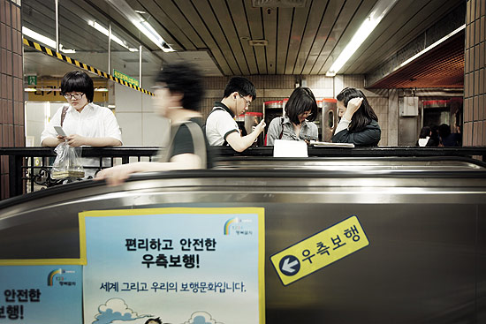 Em estação de metrô em Seul, passageiros assistem a filmes em seus telefones celulares