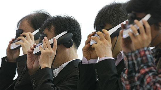 Visitantes da feira Ceatec Japan 2011 experimentam o headset Personal 3D Viewer HMZ-T1, da Sony