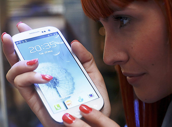Vendedora posa com o celular Samsung Galaxy S 3, em Londres