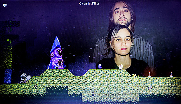 O casal Amora, 26, e Pedro Medeiros, 26, em frente  imagem do jogo "Out There Somewhere" do estdio MiniBoss, fundado por eles