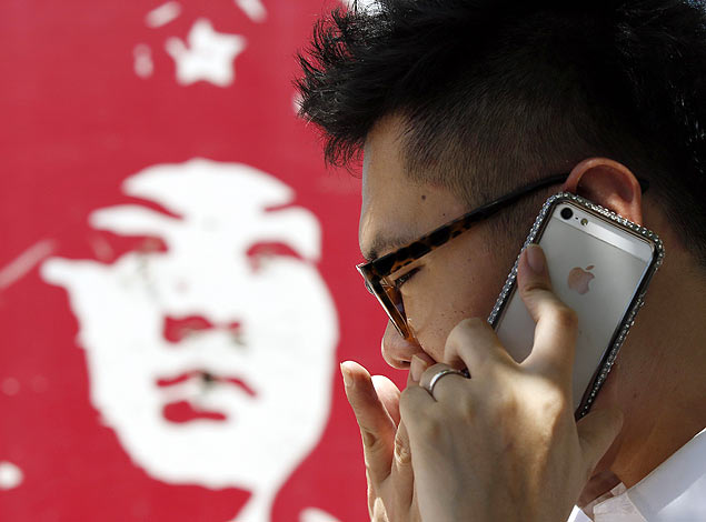 Usurio de iPhone em frente a um painel na capital chinesa, Pequim; Apple pode estar prxima de parceria com China Mobile