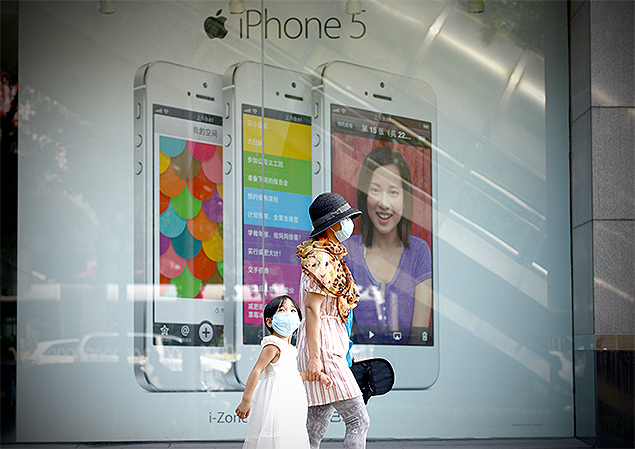 Pessoas passam em frente a um anncio do iPhone 5 em Pequim; acordo com China Mobile decepciona