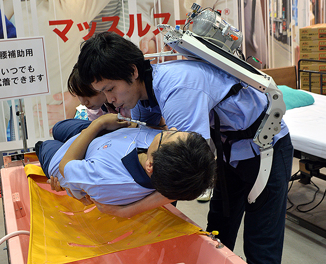 Funcionário do centro de ajuda a idosos Asahi Sun Clear demonstra o "robô vestível" desenvolvido pela Universidade de Ciência de Tóquio durante feira de robótica na capital nipônica