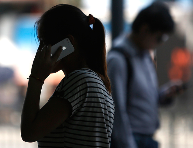 Mulher fala usando seu iPhone em rua de Xangai; acordo com China Mobile pode render bilhes anuais  Apple