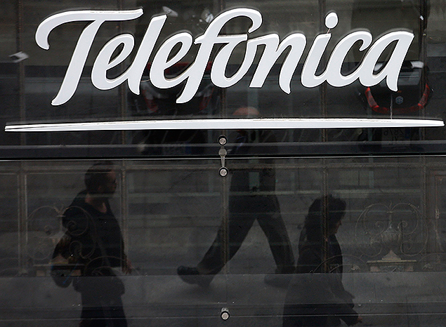 People are reflected as they walk past Spanish telecom group Telefonica's flagship store in central Madrid November 8, 2013. Telefonica on Friday posted a sharp drop in nine-months earnings, which overshadowed its progress on cutting debt and efforts to revive a loss-making investment in Telecom Italia. REUTERS/Sergio Perez (SPAIN - Tags: BUSINESS TELECOMS) ORG XMIT: MAD12