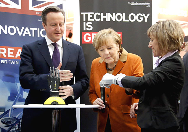 Primeiro ministro britnico, David Cameron, e a chanceler alem, Angela Merkel, examinam mo binica durante visita  CeBIT 