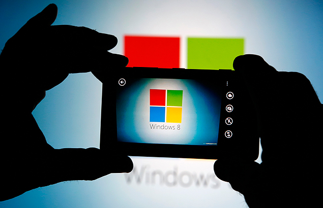 Homem usa celular da Nokia para fotografar logotipo da Microsoft, empresa que comprou a fabricante finlandesa
