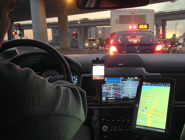 Motorista do Uber em carro com smartphone, tablet e tela de navegao integrada em San Francisco