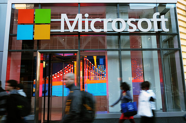 People walk past a Microsoft office in New York on October 6, 2015. Microsoft introduced a pair of big-screen smartphones and a laptop during an event in New York on Tuesday. The company unveiled the Surface Book, a laptop with 13.5-inch detachable touchscreen, the Surface Pro 4 tablet and the Lumia 950 and 950 XL smartphones, which feature displays measuring over 5 inches. The Surface devices launch later this month, while the Lumias arrive in November. AFP PHOTO/JEWEL SAMAD ORG XMIT: JS3057