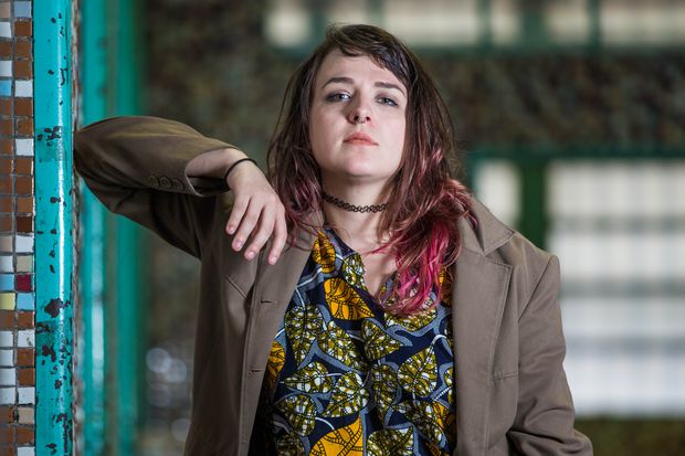 Débora Baldin, do Canal das Bee, tem cabelo com mechas rosas e olha fixamente para a câmera