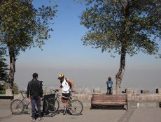 Ciclistas no Cerro San Cristóbal; ao fundo, vemos a poluição cobrindo Santiago