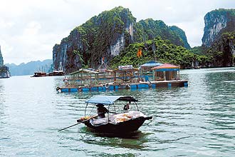 Barco de pescador cruza embarcao em Halong Bay; local  boa opo para quem quer descansar do estresse do trnsito de Hani