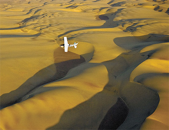Imagem area mostra um pequeno avio Cessna sobre dunas do parque Costa do Esqueleto