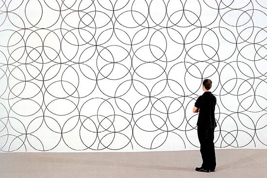 Homem observa "Composition With Circles 2", desenho sobre a parede de Bridget Riley