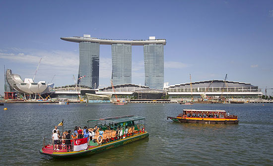 Botes lotados de turistas passam em frente ao resort e casino Marina Bay Sands, inaugurado em 2010