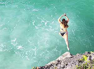 Mulher mergulha no mar de Barbados; visitantes podem conhecer ilha de norte a sul em uma hora de viagem