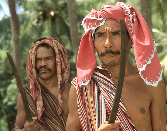 Homens vestindo o tradicional tecido colorido "tai" fazem cerimônia de boas vindas na ilha Atauro, no Timor Leste