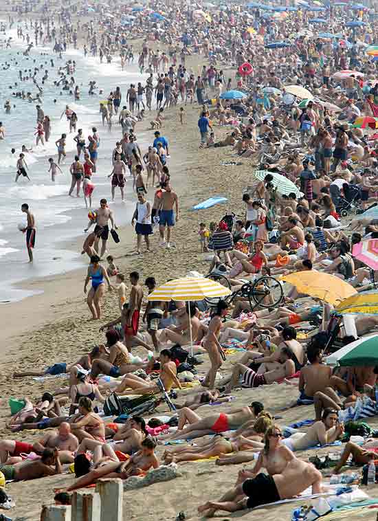 Turistas na praia de Barceloneta, em Barcelona, Espanha