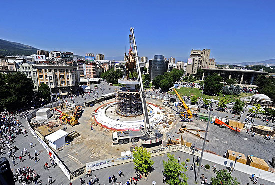 Trabalhadores elevam a esttua de Alexandre sobre pedestal na praa central de Skopje
